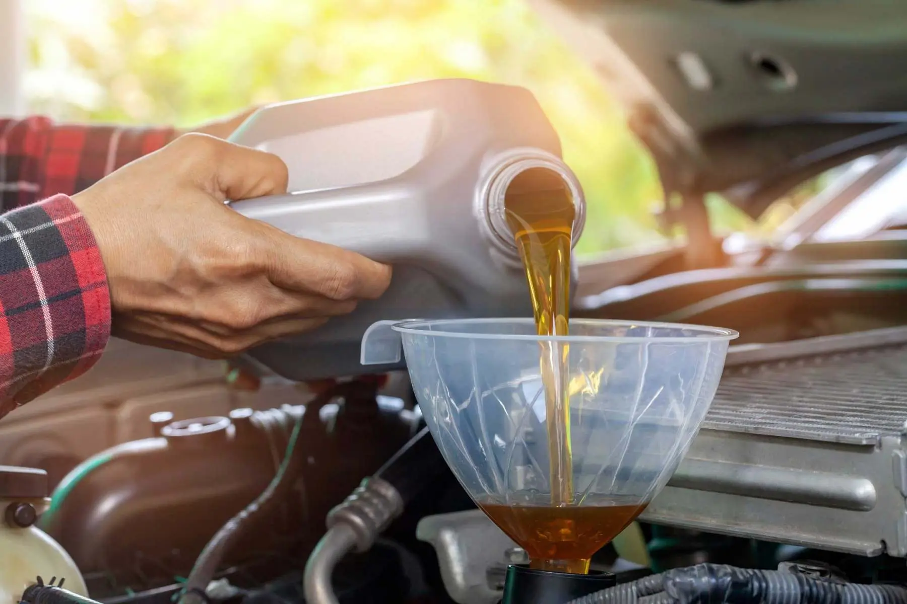 Mechanic pouring new oil into a car engine during a service at C.A.M.S. garage Chippenham